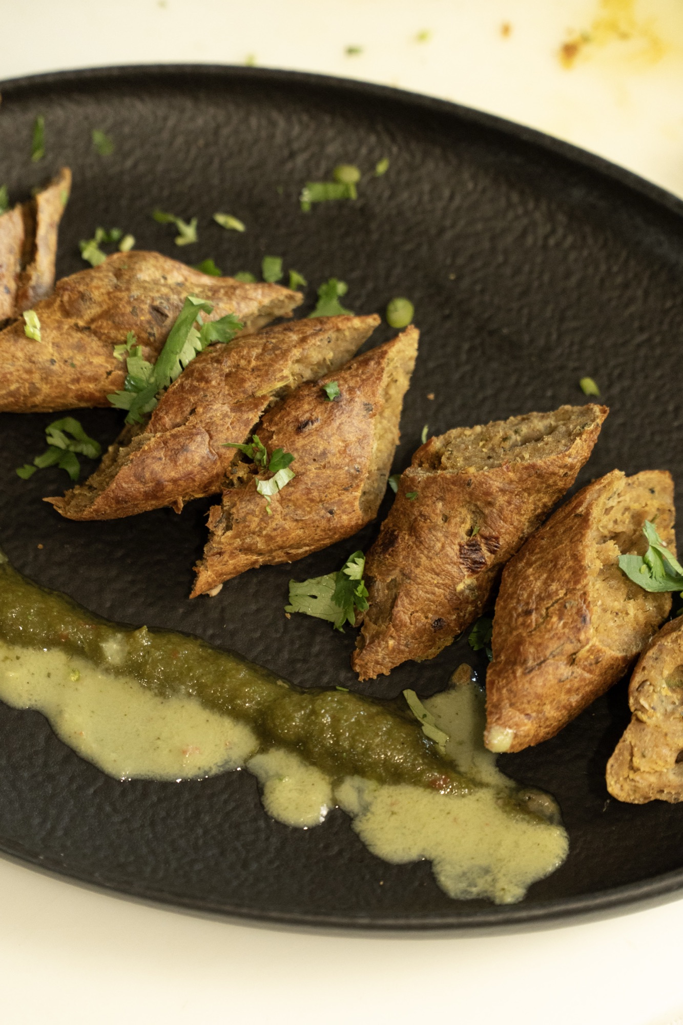 Kebabs with green chutney on black plate